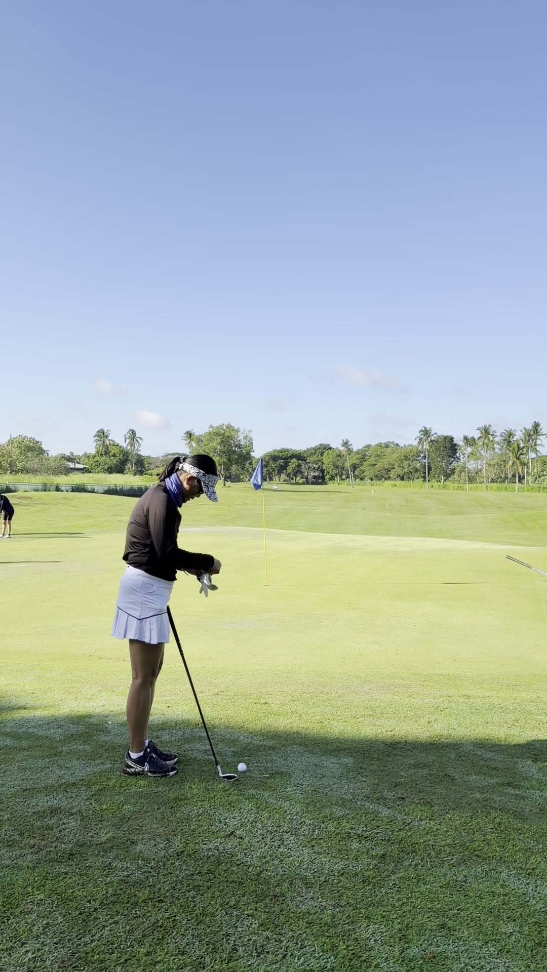 Golfer adjusting her golf glove before a putt on the green
